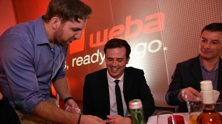 weba Werkzeugbau TechDays - Gala-Event und VIP-Abend Entertainer Michal Sindelar führt während des Gala-Events zwei Personen auf dem Dinnertisch seine faszinierenden magischen Tricks vor