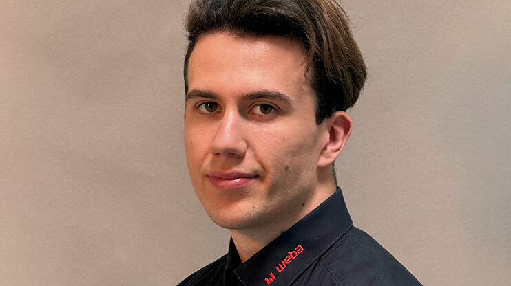 Porträtfoto von Michal Urbuś, IT-Techniker bei weba Werkzeugbau, in schwarzem Hemd mit rotem weba-Logo vor neutralem Hintergrund.