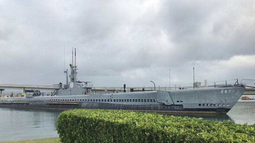 USS Bowfin – Das „Pearl Harbor Avenger“ Ein historisches U-Boot im Hafen von Pearl Harbor, Hawaii, unter einem wolkigen Himmel.