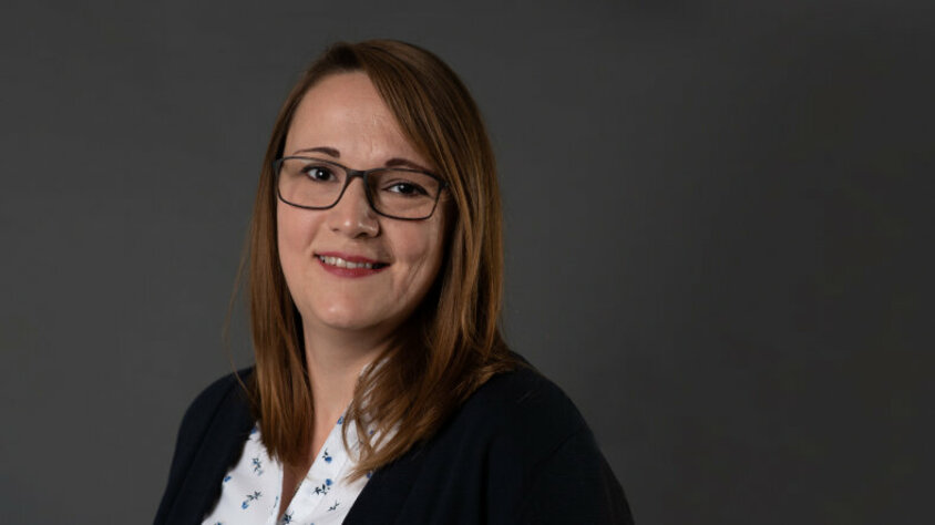 Melanie Kampenhuber – Produktionsassistentin bei weba Melanie Kampenhuber, Produktionsassistentin bei weba, lächelt freundlich in die Kamera. Sie trägt eine Brille und ist in professioneller Kleidung abgebildet, vor einem neutralen Hintergrund.