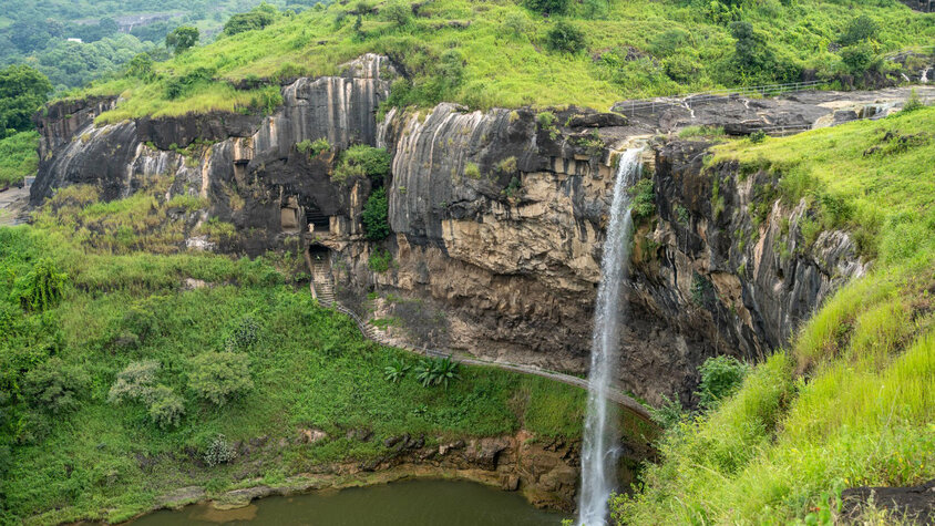 Malerischer Wasserfall inmitten grüner Landschaften Ein beeindruckender Wasserfall stürzt von einer steilen Klippe in ein ruhiges Becken, umgeben von üppigem Grün und felsigen Formationen.