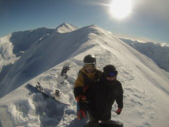 Tomáš Novotný snowboarding in the mountains with a view of snow-covered peaks