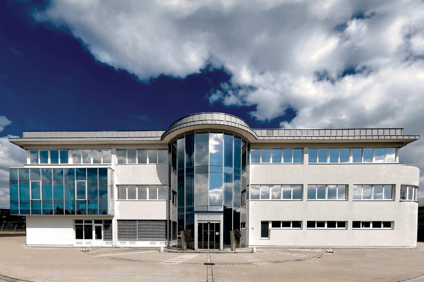 Außenaufnahme des Verwaltungstraktes der Entwicklungszentrale von weba in Dietach unter einem blauen Himmel mit Wolken.