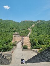Blick entlang der Chinesischen Mauer, die sich über grüne Hügel und Täler erstreckt, mit Besuchern auf dem Weg – eine Station aus Jan Wengryns Zeit in China.