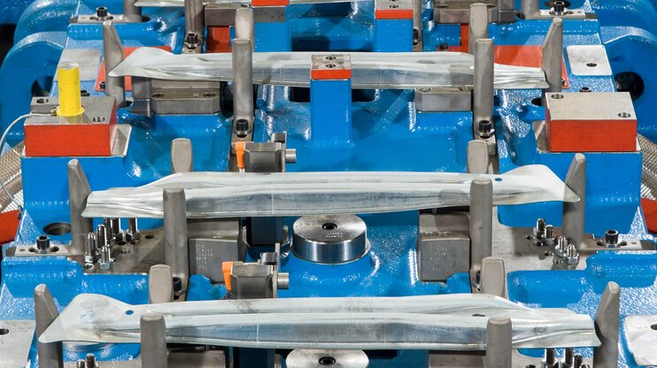 Transfer die for cold forming in detail: multiple fixed sheet metal parts in a precisely manufactured tool for producing door impact beams in the automotive industry.
