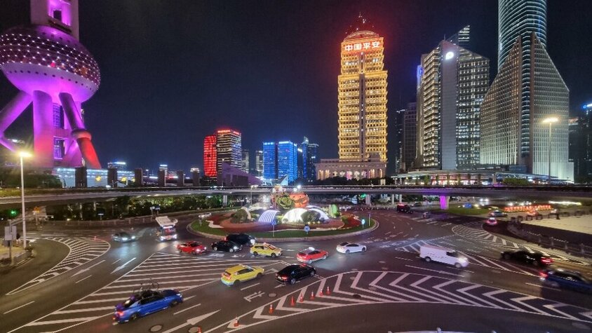 Nächtliche Straßenansicht im Finanzviertel von Shanghai mit beleuchteten Hochhäusern, der Oriental Pearl Tower im Hintergrund und dichtem Verkehr auf den Straßen – Momentaufnahme aus Jan Wengryns Zeit in China.