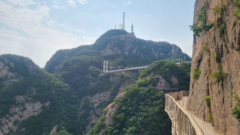 Blick auf eine Hängebrücke in den Bergen Chinas, umgeben von dichtem Grün und Felswänden – eine Aufnahme aus Jan Wengryns Zeit im Auslandseinsatz.