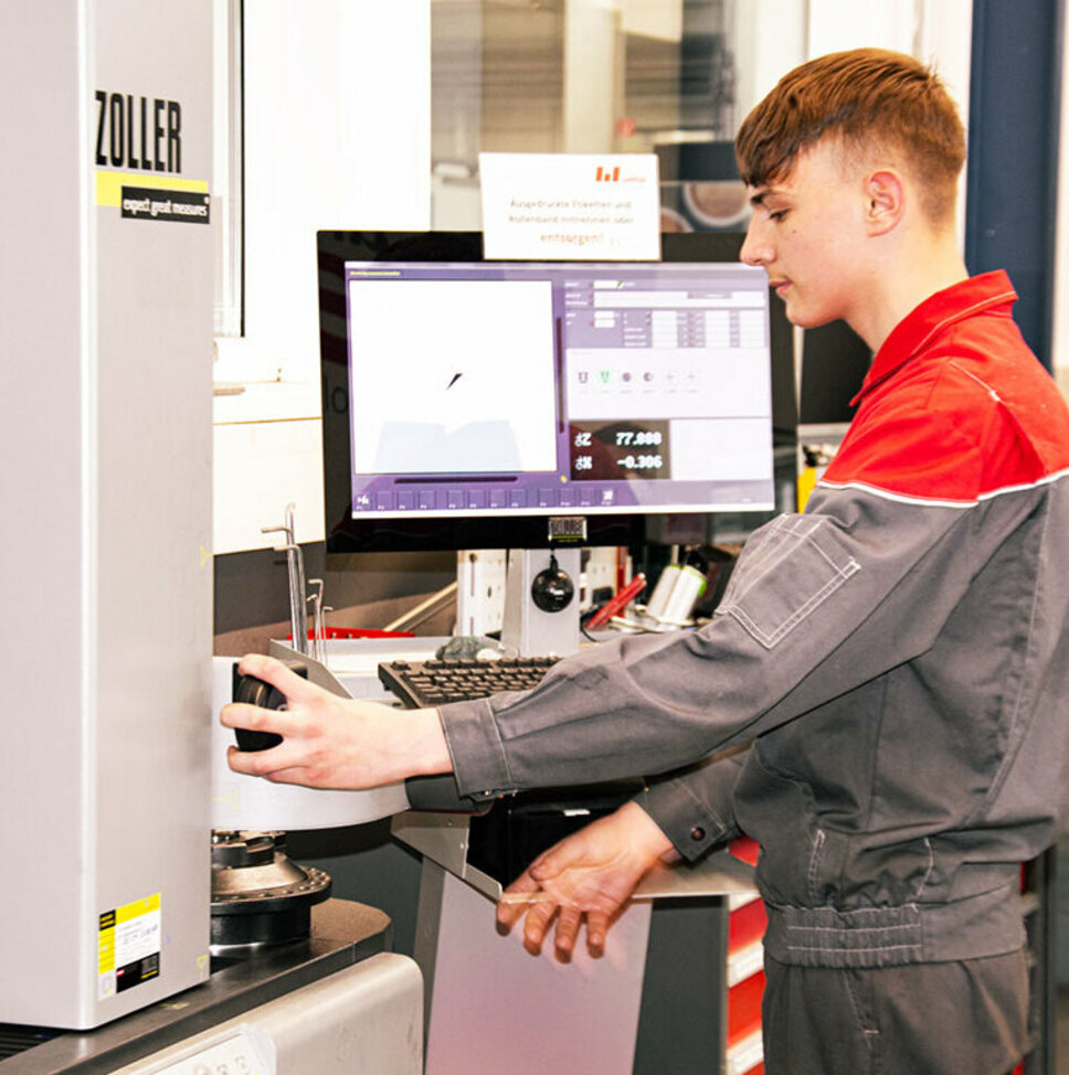 Ein Lehrling aus der Metalltechnik arbeitet konzentriert an einer technischen Anlage.