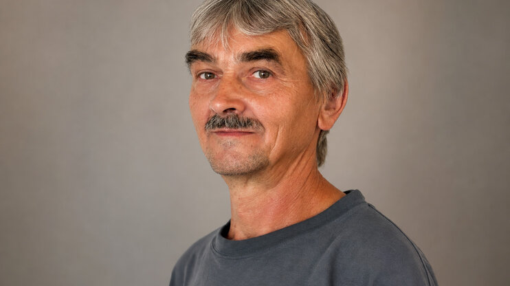 Professional portrait of František Krumpolec against a subtle grey studio background.
