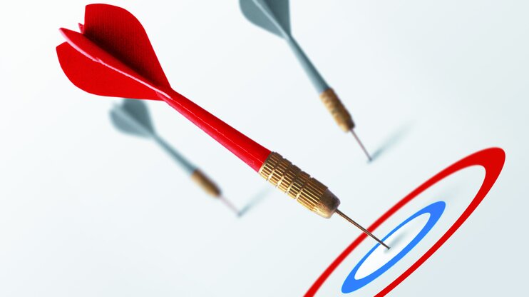 Roter Dartpfeil trifft genau ins Bullseye, zwei graue Pfeile verfehlen das Ziel – Symbol für klare Zielsetzung mit der SMART-Methode.