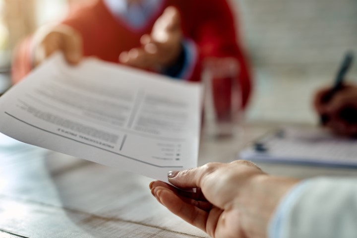 A letter of application is passed from one hand to the other.
