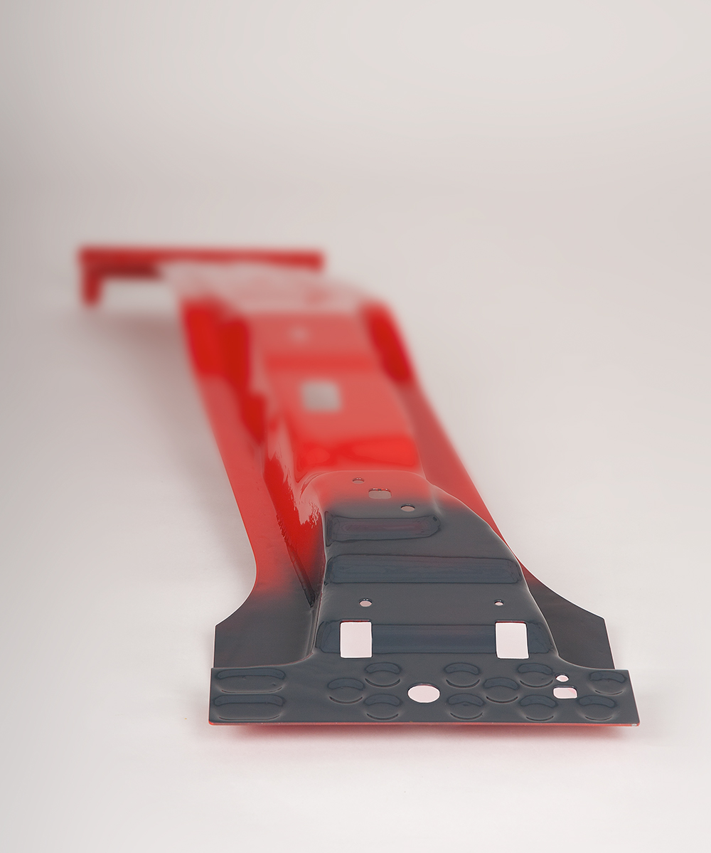 Eine B-Säule, gefertigt aus höchstfestem Material, präsentiert sich in einem leuchtenden Rot. Besonders hervorgehoben ist eine Softzone, die für maßgeschneiderte Crasheigenschaften entwickelt wurde; diese Zone hebt sich in einem tiefen Anthrazitgrau deutlich vom restlichen Teil der Säule ab. Die Kontrastierung der Farben betont die speziellen Eigenschaften der B-Säule und die technische Innovation, die hinter der Entwicklung maßgeschneiderter Sicherheitsmerkmale steht. 