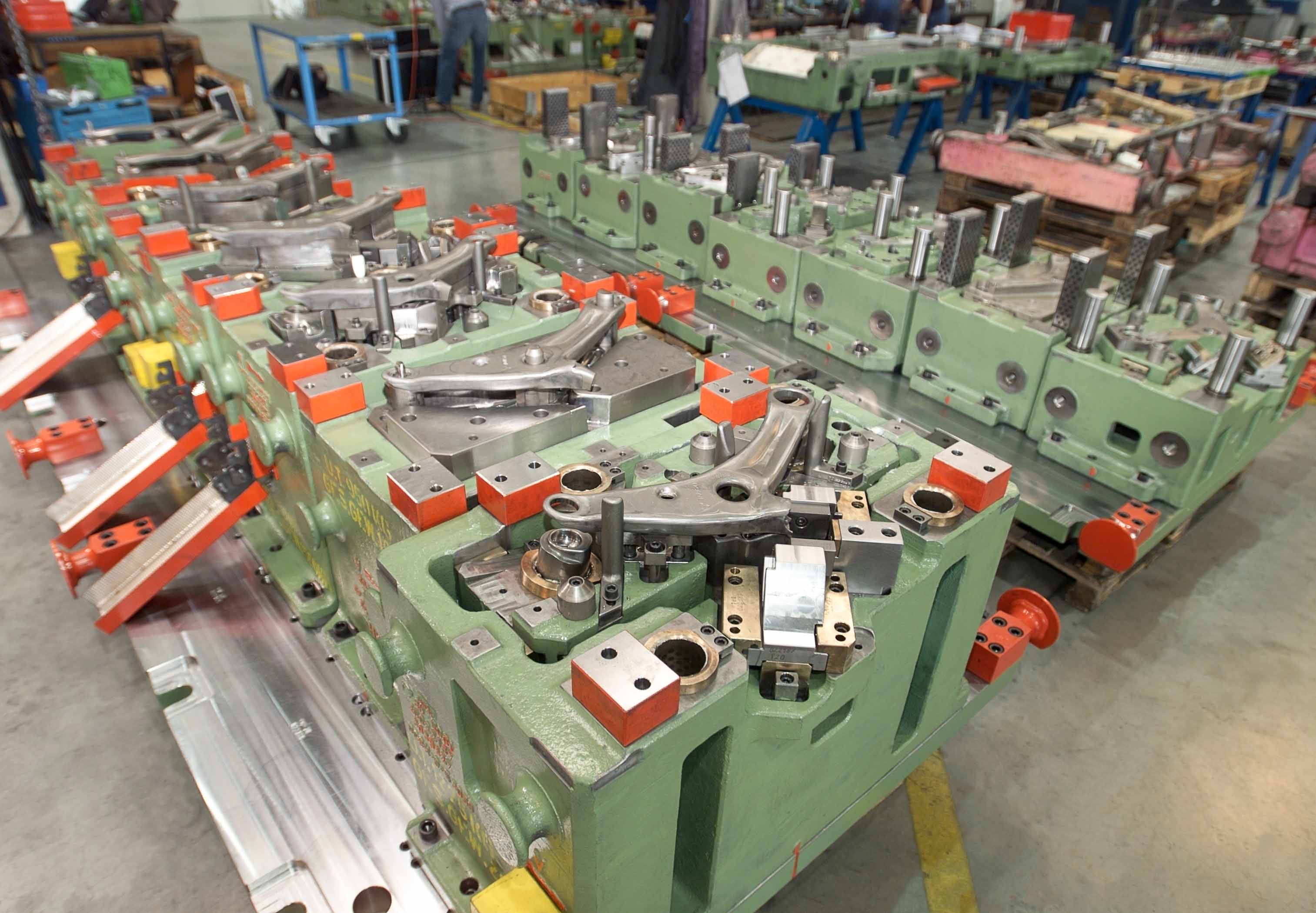 Transferwerkzeug für einen Querlenkerarm in der Automobilproduktion; komplexe Werkzeugaufspannung mit mehreren Formnestern und mechanischen Einheiten in der Werkhalle von weba Werkzeugbau.
